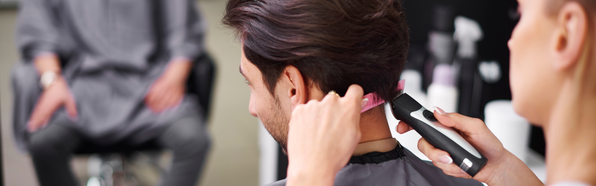 Ein Friseur von Team-Eser schneidet präzise die Seitenhaare eines Mannes mit einer Haarschneidemaschine, für einen sauberen und modernen Männerhaarschnitt im Salon in Nilkheim.